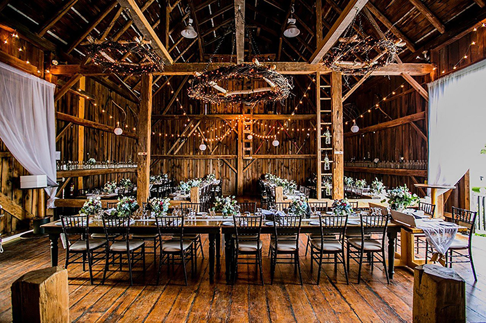 Inside the Brooklands Farm heritage barn with timber beams, harvest tables and string lights